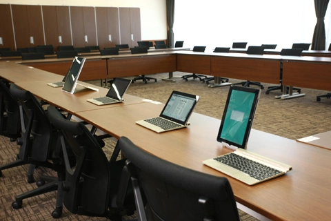庁議が行われる会議室とタブレット端末。会議用資料の紙の削減と会議運営の効率化に貢献